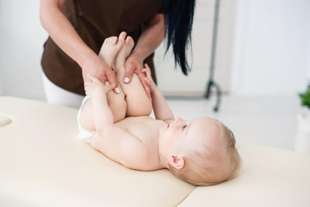 Osteopathiebehandlung für Babies Eine Frau behandelt ein Baby mit Osteopathie